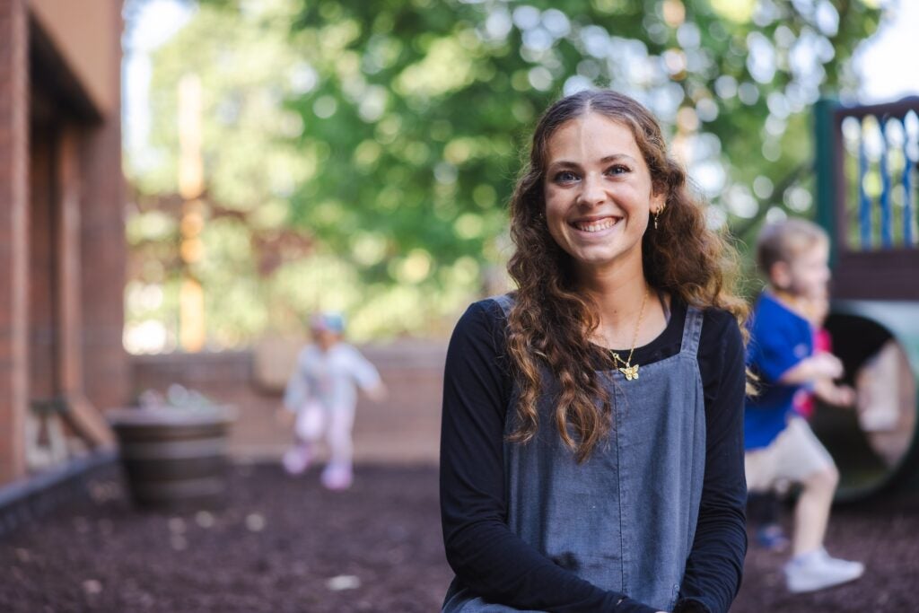 college student smiling at the camera while sitting at a playground