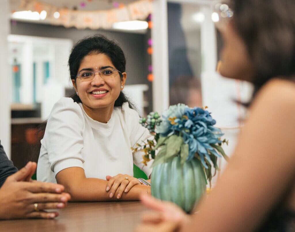 student talking to two other students inside at a table