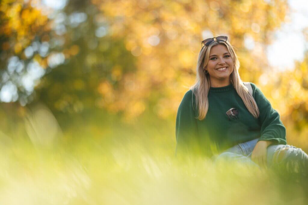 student on campus in the fall smiling at the camera