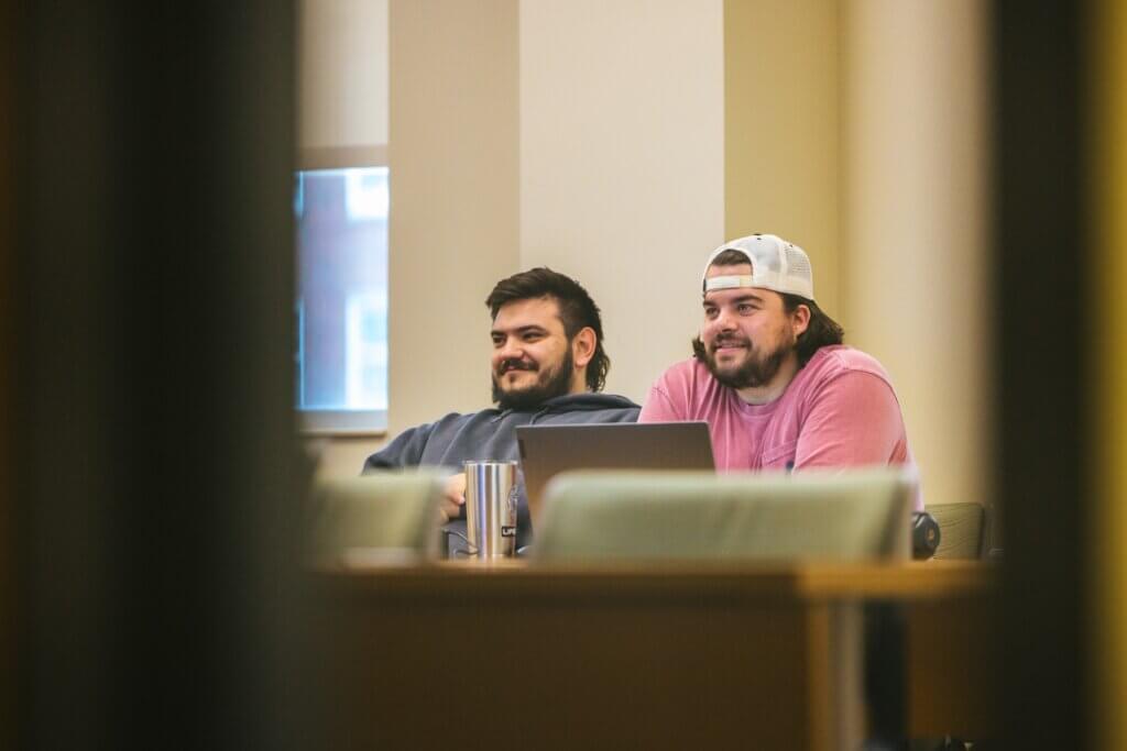 two students in a classroom listening to a lecture