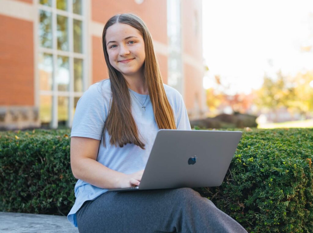 student working on a laptop outside the library