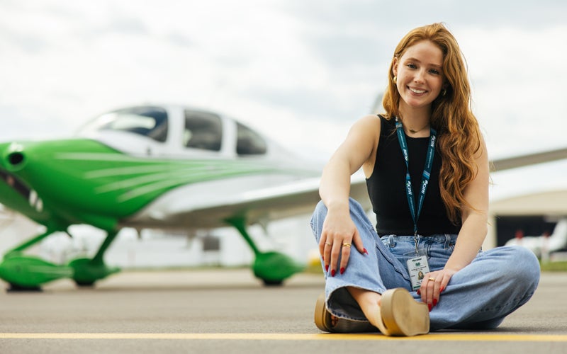 A student in Marshall University's Bill Noe Flight School sits in front of at Marshall branded plane