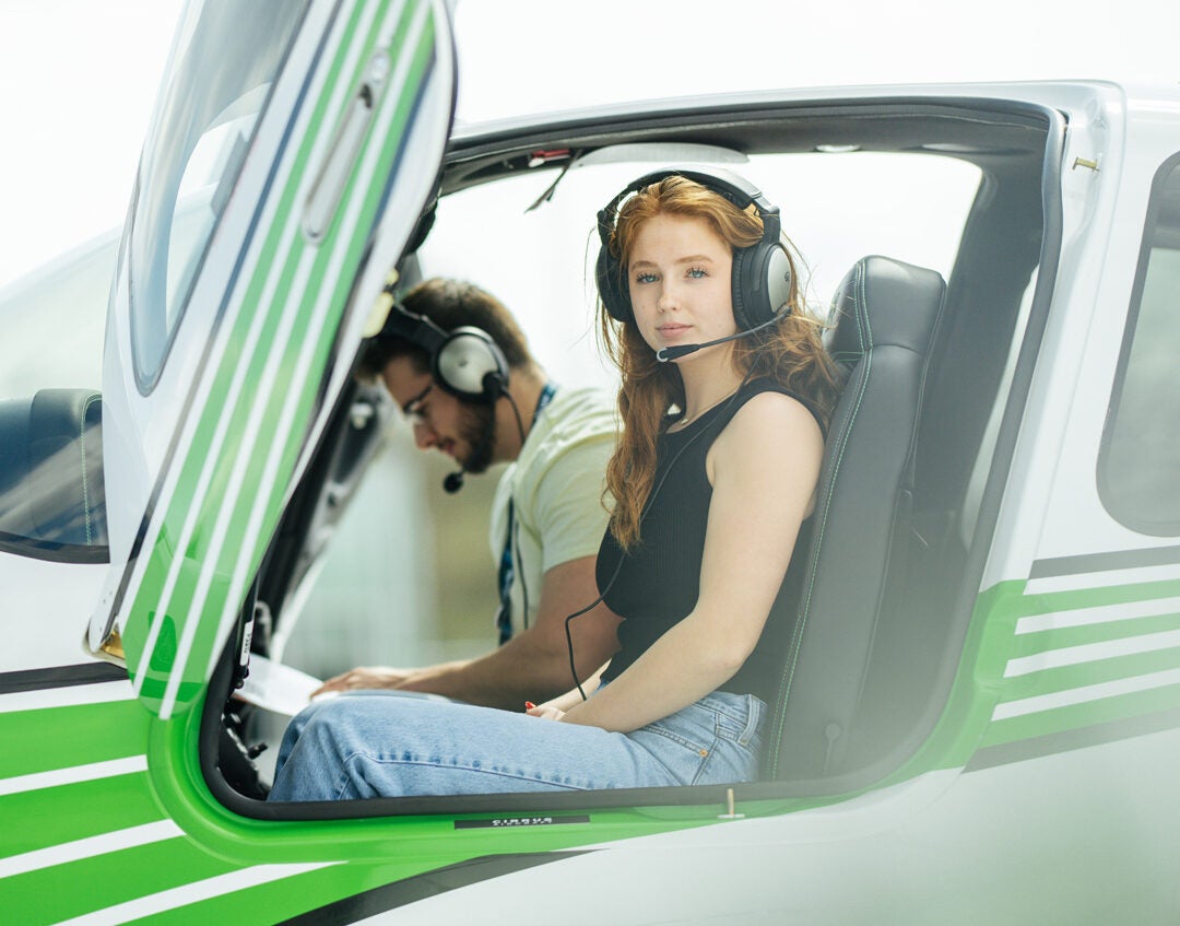 A Marshall University Bill Noe Flight School student looks at the camera while in the pilot seat of a Marshall branded aircraft.