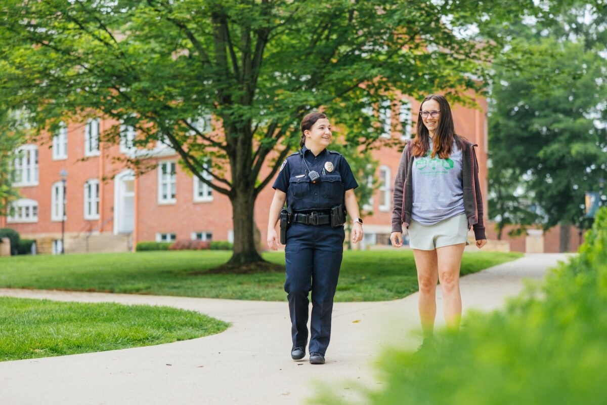 student walking and talking to a police officer on campus