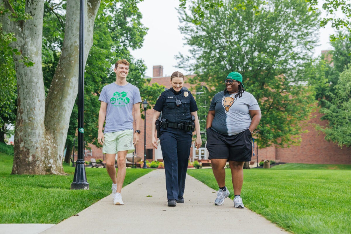 two students walking with a police officer on campus