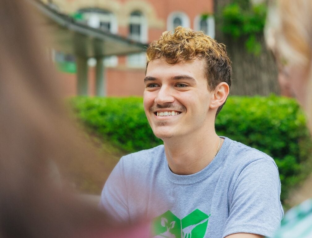 student outside on campus smiling off camera