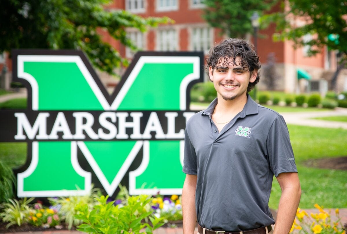 photo of criminal justice student in front of the block M sign on campus, smiling at the camera