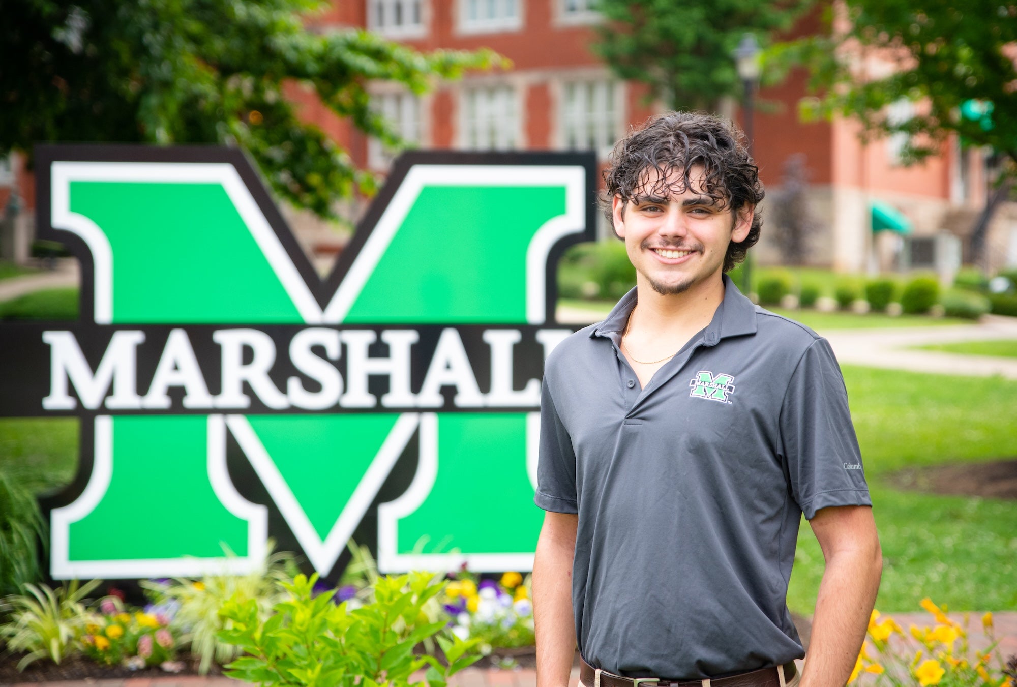 photo of criminal justice student in front of the block M sign on campus, smiling at the camera