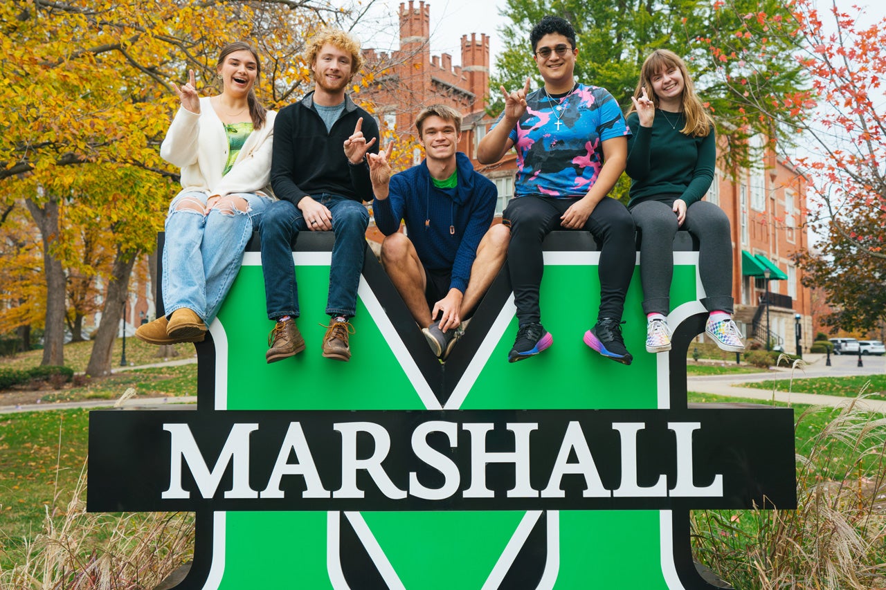 FAM student mentors pose for a photo on the M sign outside of Marshall University's Old Main.