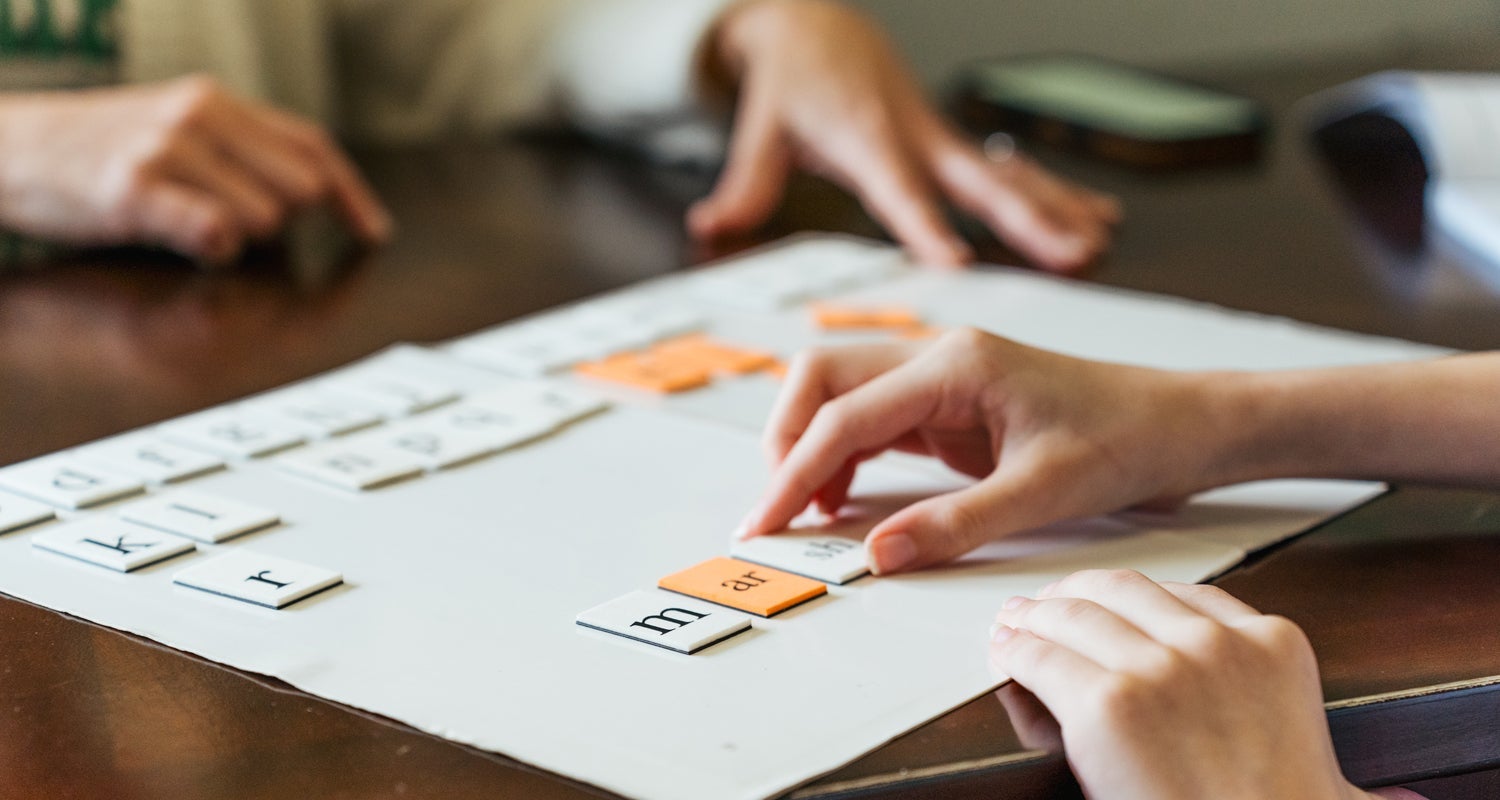 Image of hands organizing cutout letter groupings