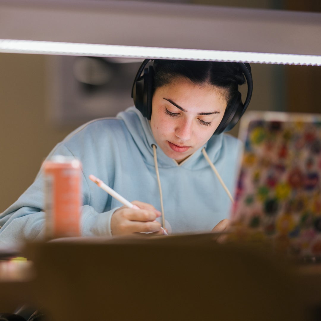 Student studies under desk lamp