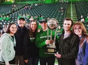 photo of the Ely family at a Marshall basketball game with a trophy