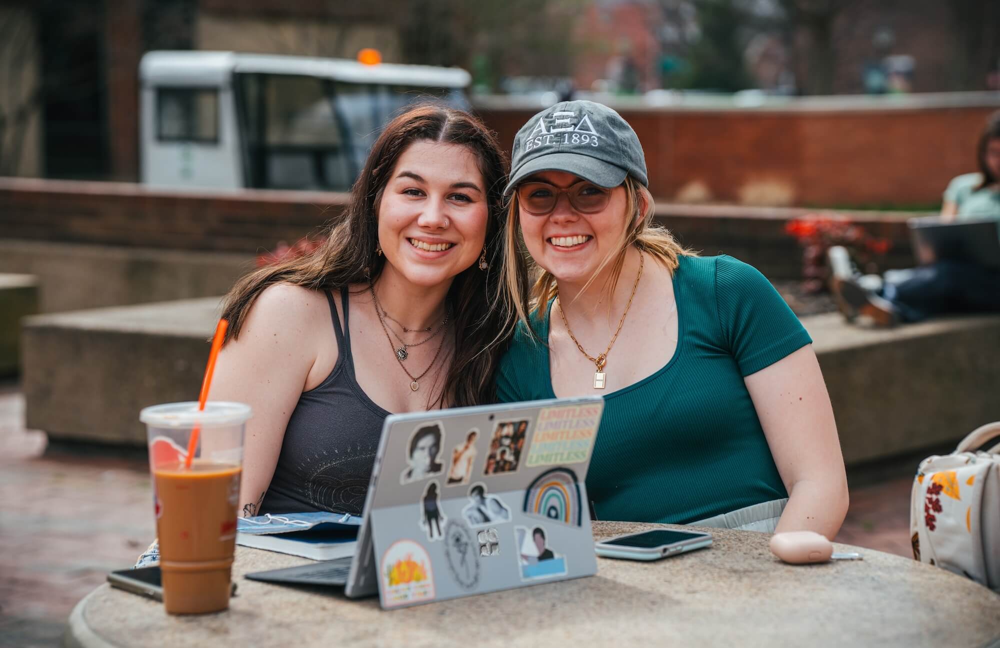 two students smiling at the camera with a laptop