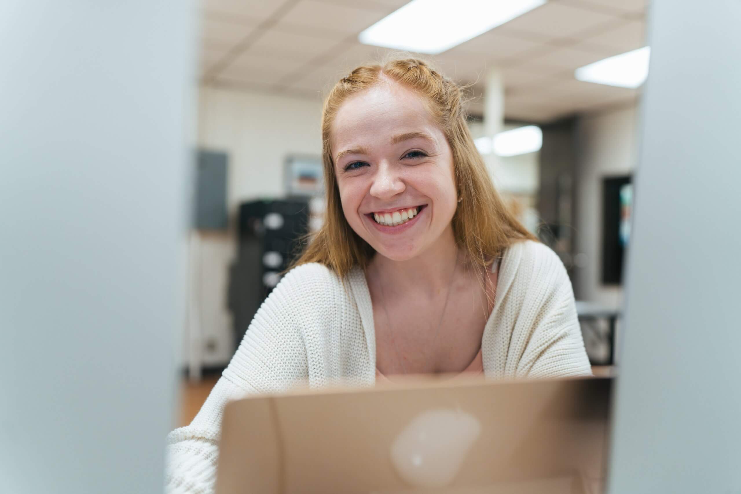 female student working on a laptop and smiling at the camera