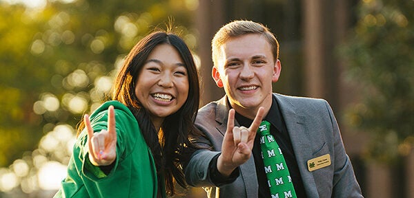 Student Government leaders smile at the camera while riding in the Marshall University Homecoming Parade