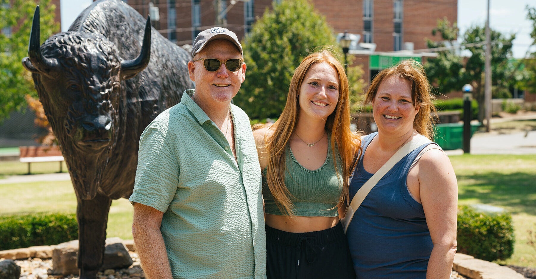 A student smiles with her family in front of a bison statue at Marshall University