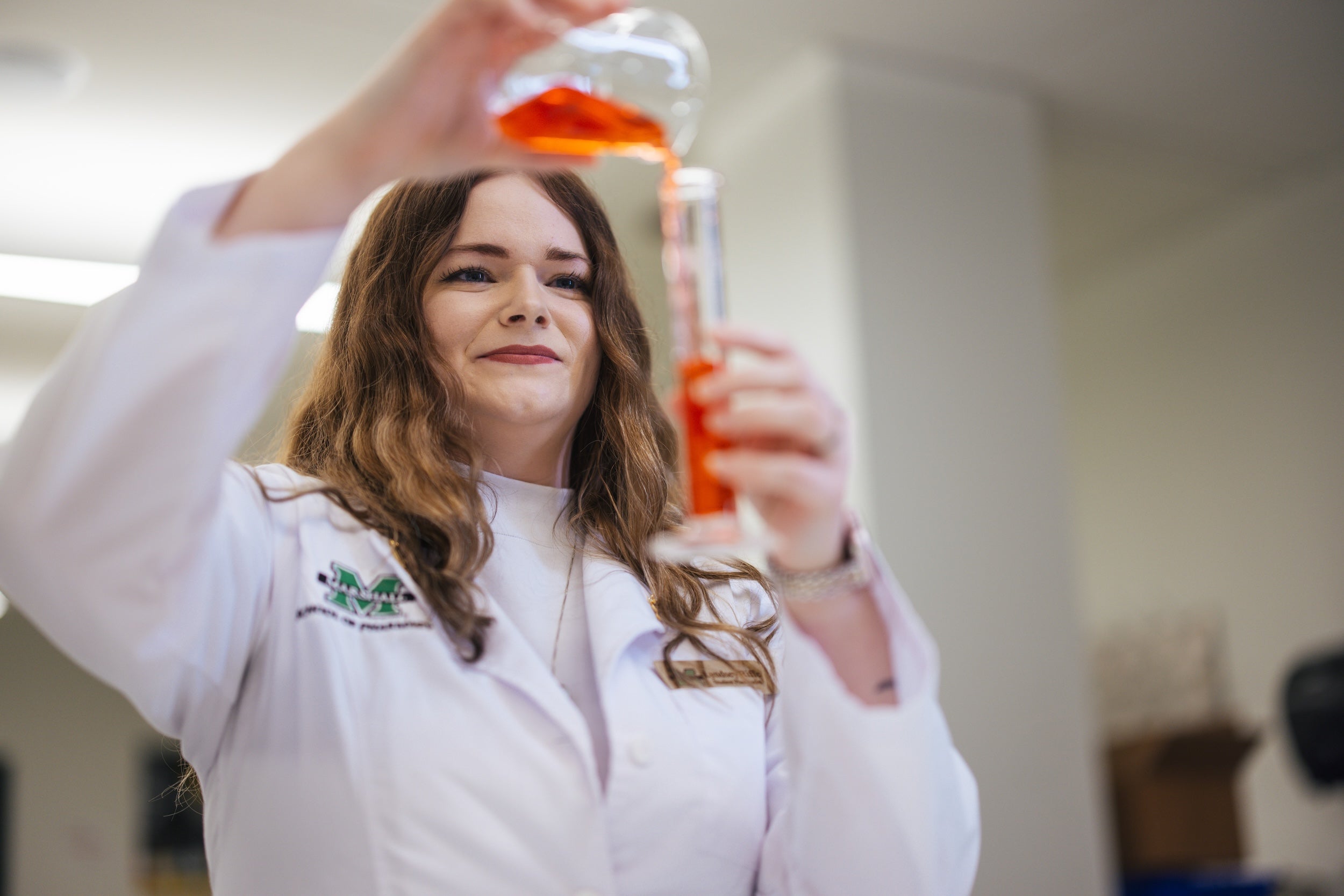 student pouring a solution in a lab