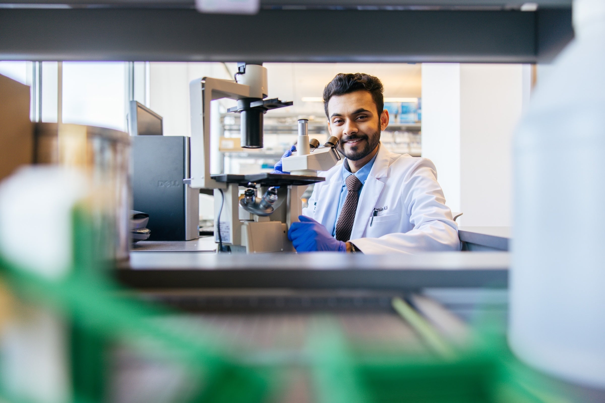 student in a pharmacy lab at a microscope