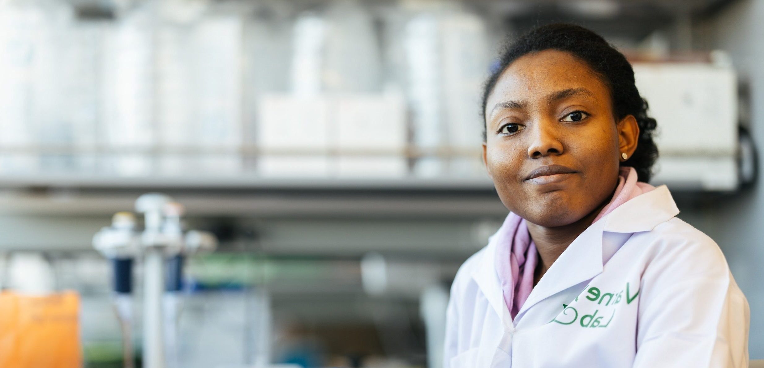 female pharmacy student in a lab and smiling at the camera