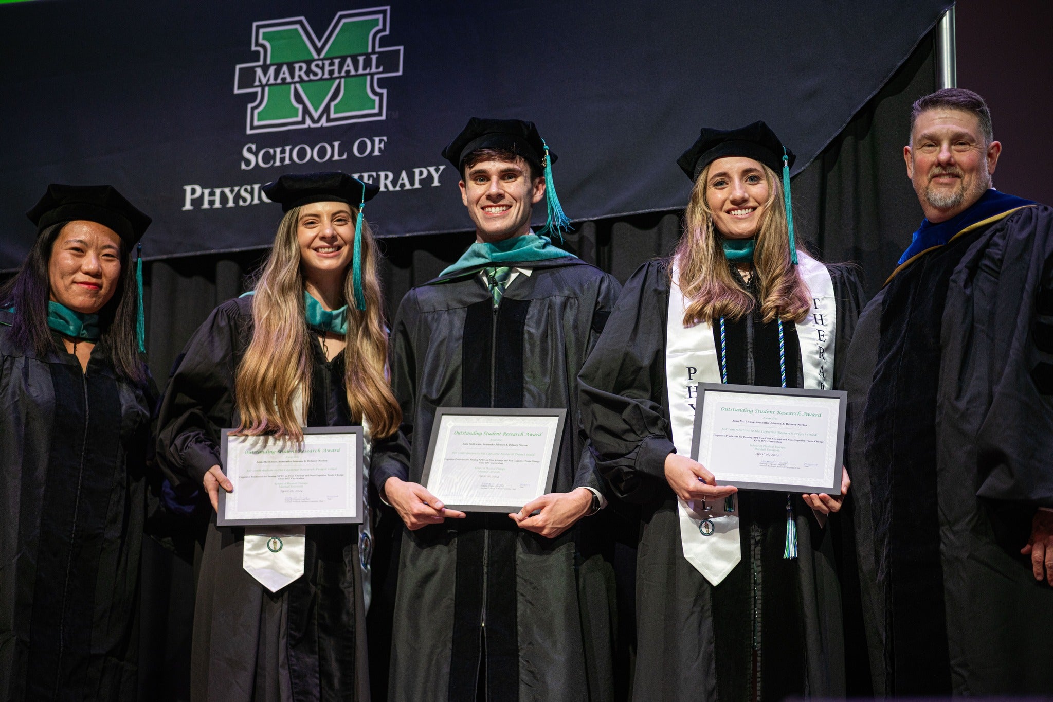 three recent doctorate of physical therapy graduates smiling with two professors
