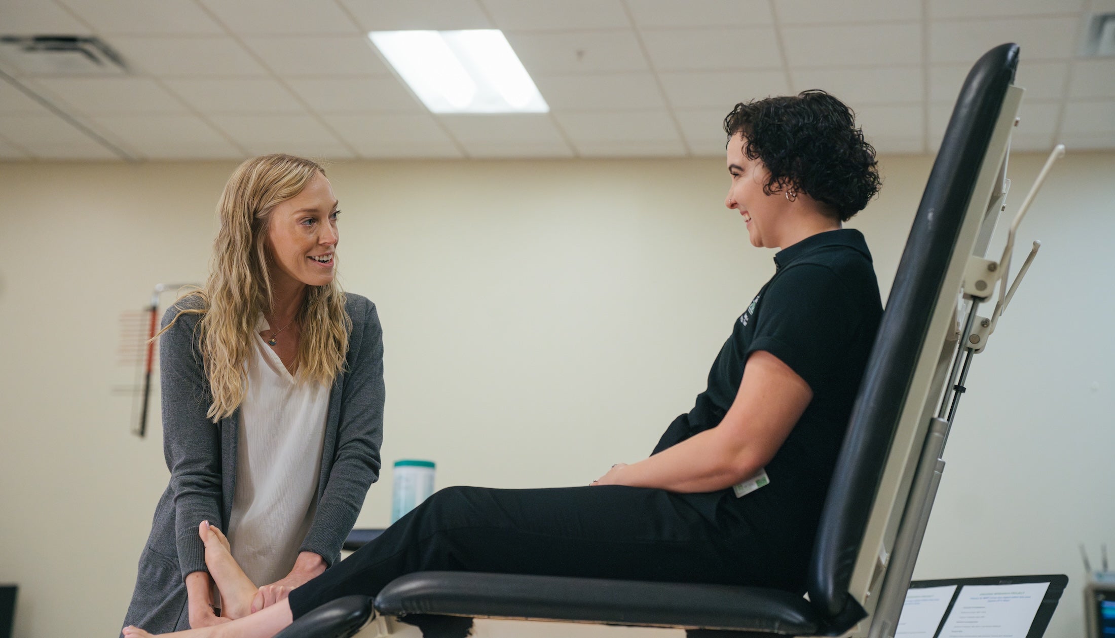 student sitting on a table talking to a professor