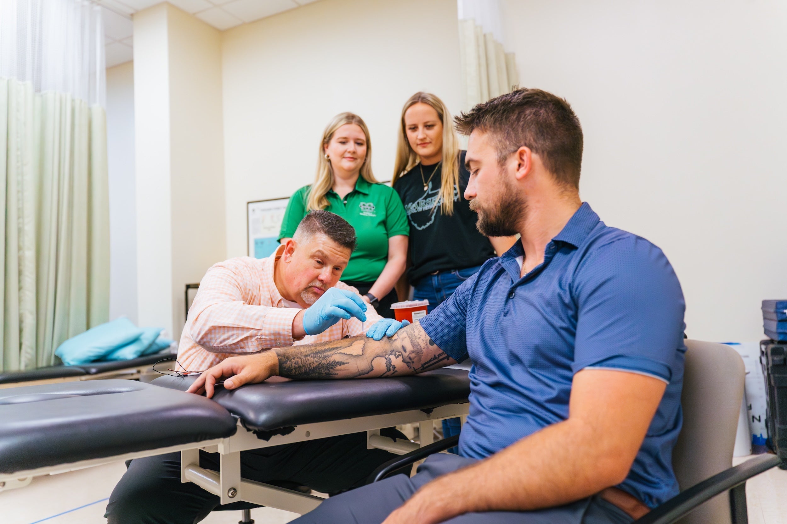 Director Davis working on a test patient, two physical therapy students observing