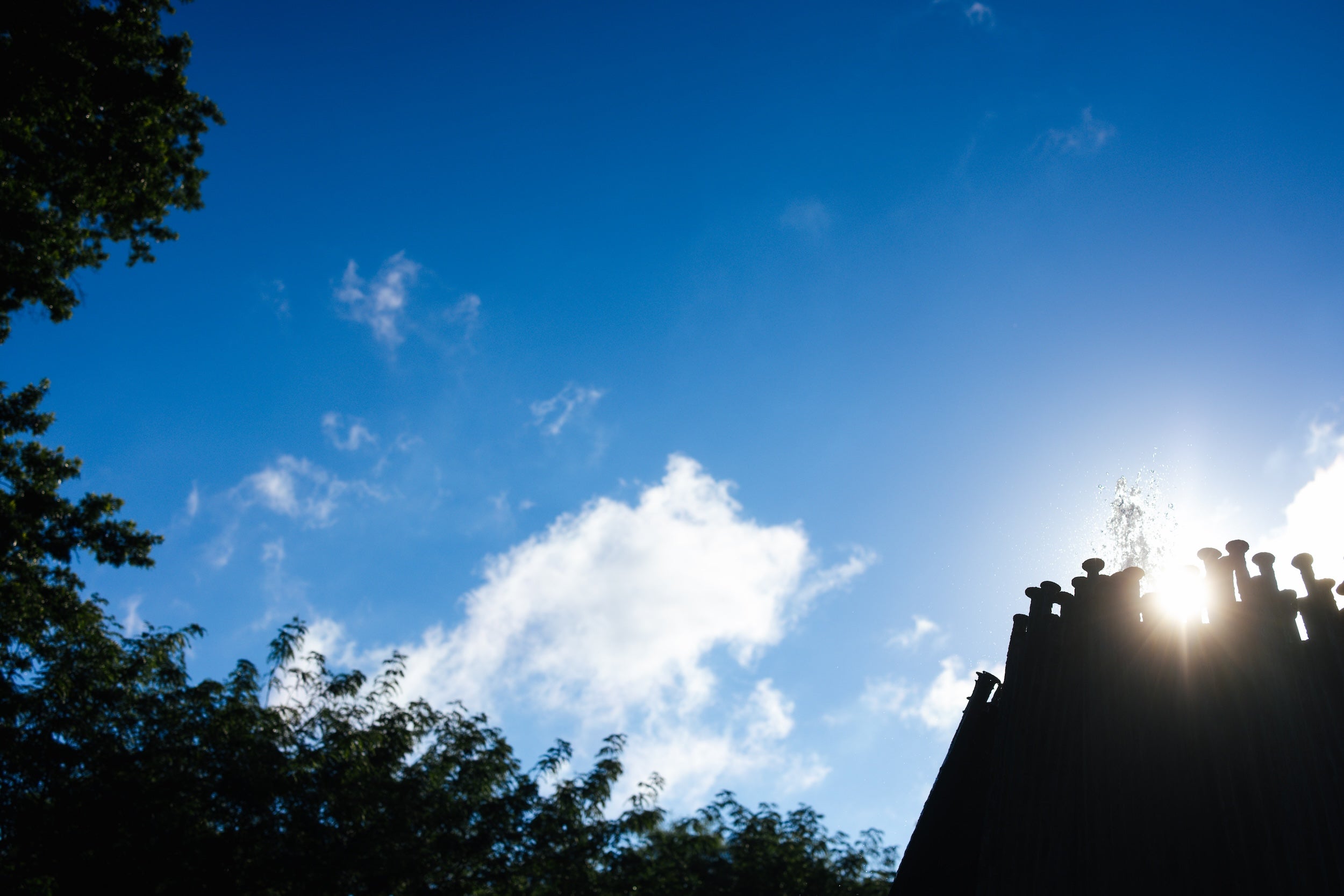 sun peeking out of the top of the Memorial Fountain