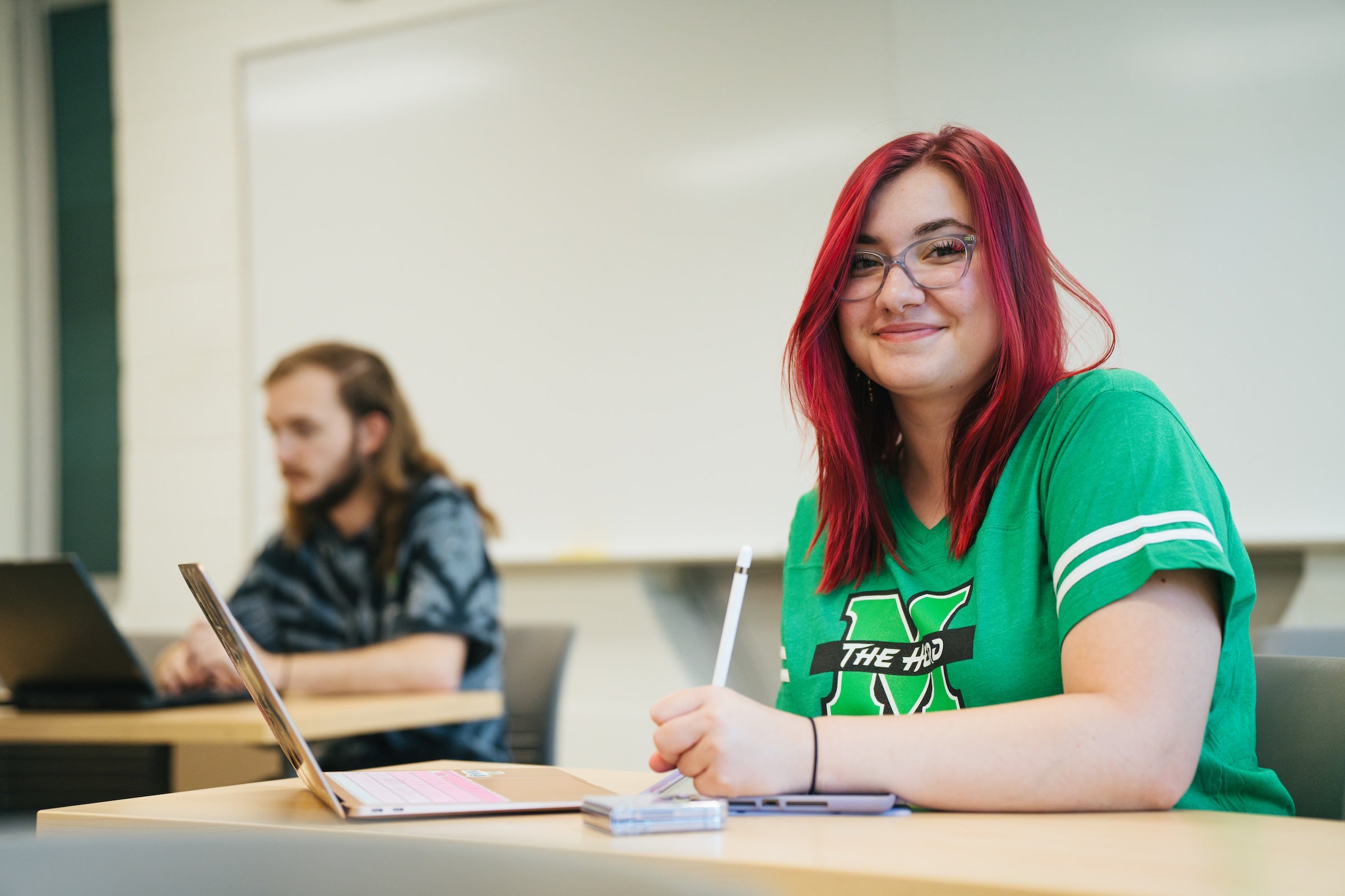 student at a desk smiling at the camera