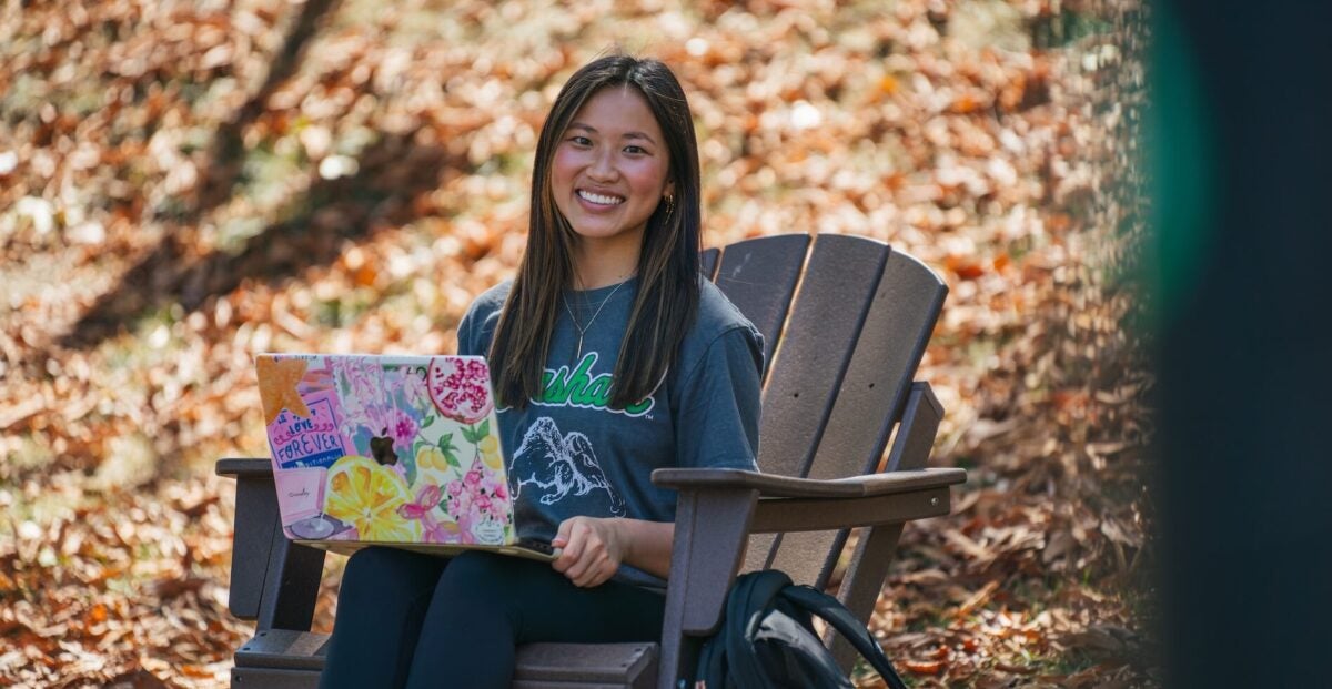 student working on a laptop outside in the fall