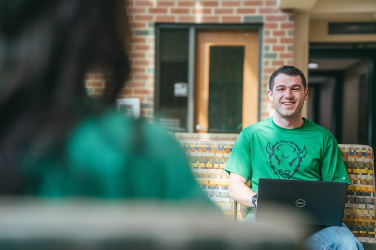 student smiling in a green t-shirt