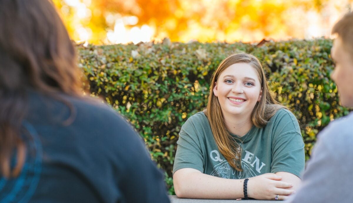 student talking to two other students outside