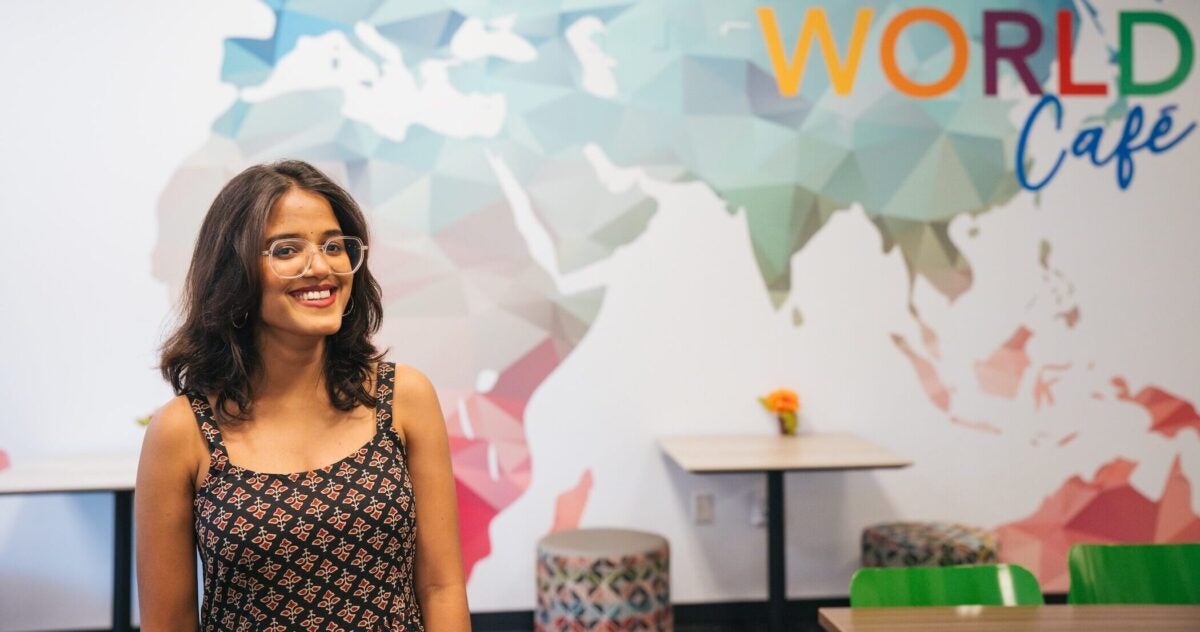 student in East Hall smiling with map behind her