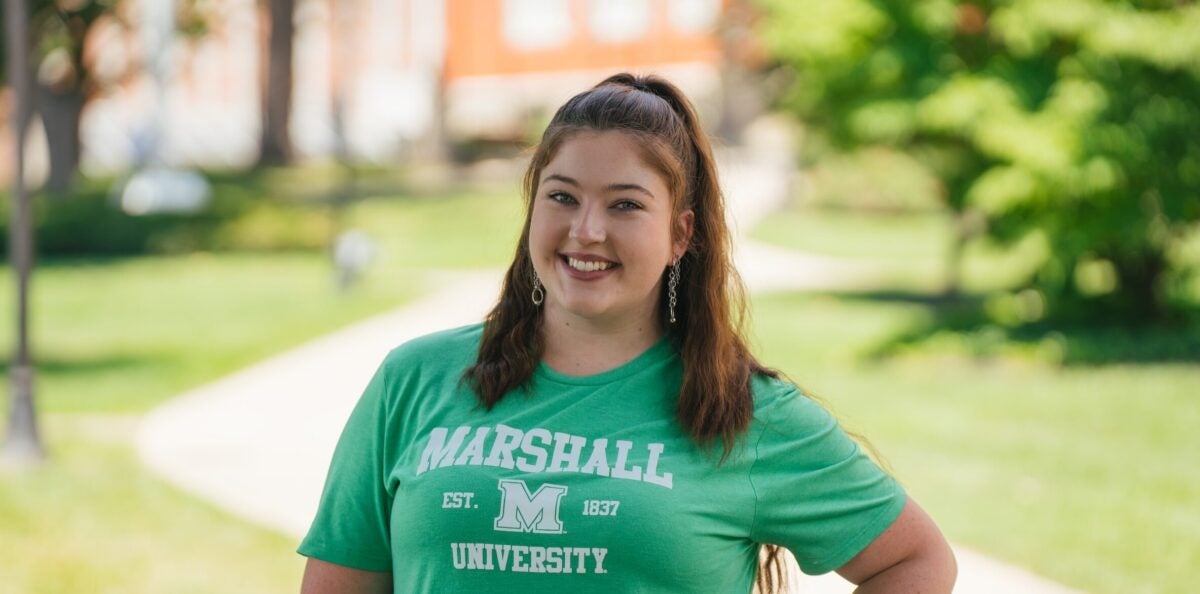 student in a Marshall shirt smiling at the camera