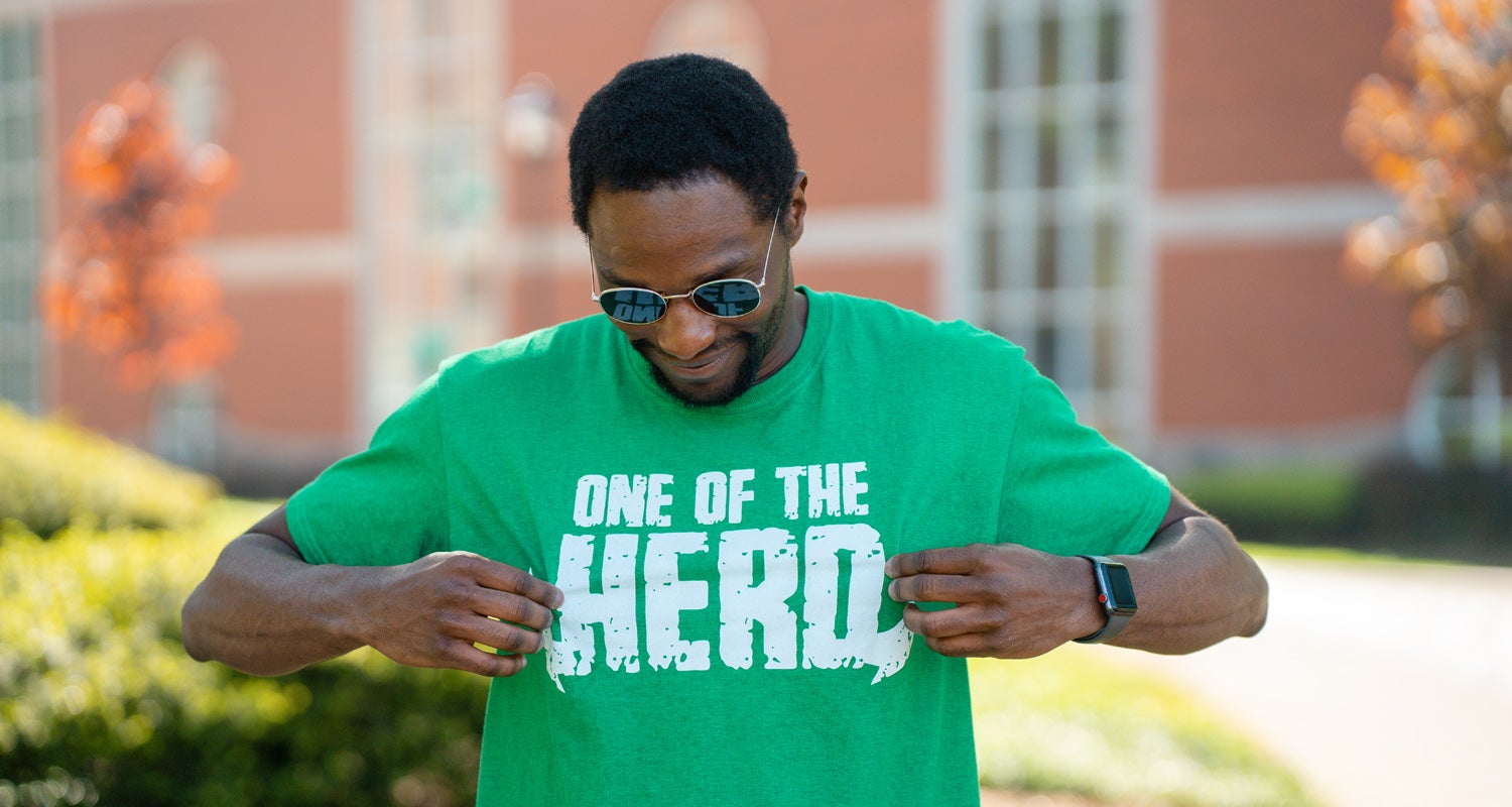 A student shows off his Marshall University t-shirt with a design that says "One of the Herd"