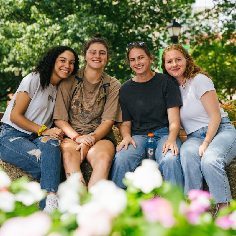 A group of four students smile for a photo on Marshall University's Memorial Student Center Plaza