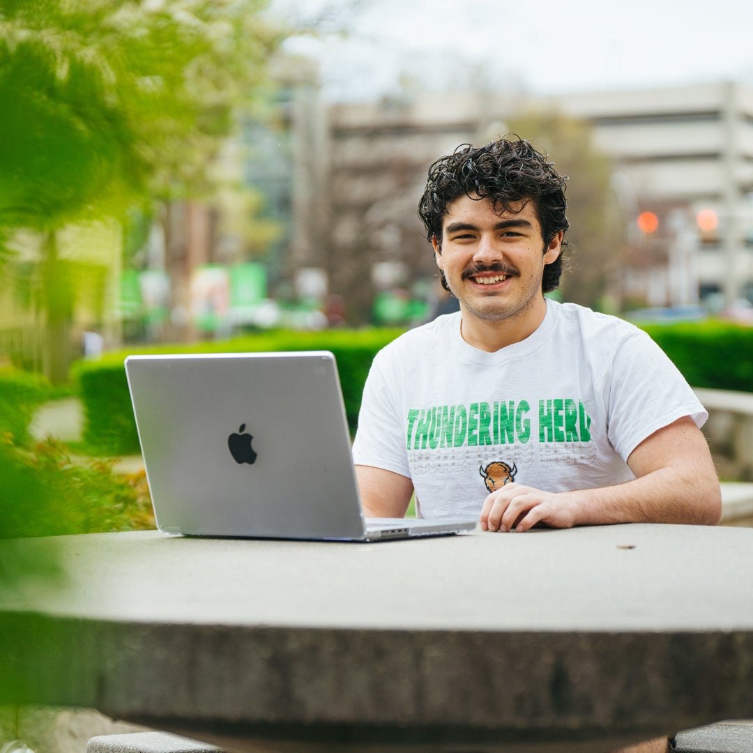 A student studies at a table outside of Marshall University's Drinko Library