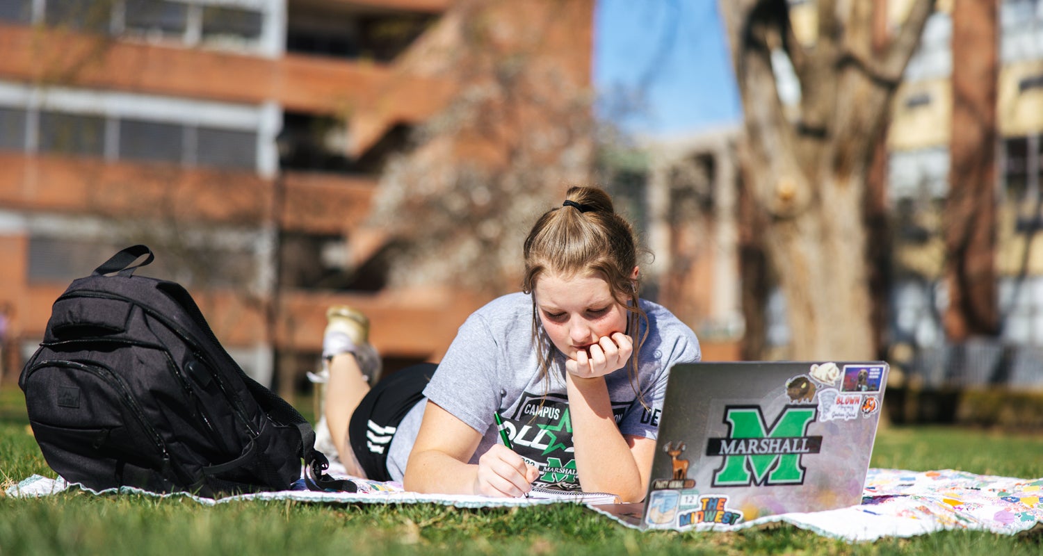 A student studies on Buskirk Field at Marshall University